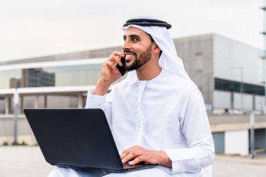 Arap Ortadoğu 'lu, Emirati Kandora giysili, şehirde geleneksel giysiler giyen Arap Müslüman iş adamı, şehir iş merkezinde geziniyor..