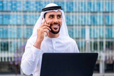 Arap Ortadoğu 'lu, Emirati Kandora giysili, şehirde geleneksel giysiler giyen Arap Müslüman iş adamı, şehir iş merkezinde geziniyor..