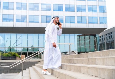 Arap Ortadoğu 'lu, Emirati Kandora giysili, şehirde geleneksel giysiler giyen Arap Müslüman iş adamı, şehir iş merkezinde geziniyor..