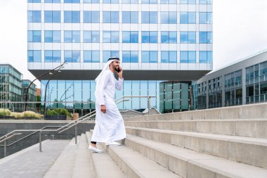 Arap Ortadoğu 'lu, Emirati Kandora giysili, şehirde geleneksel giysiler giyen Arap Müslüman iş adamı, şehir iş merkezinde geziniyor..