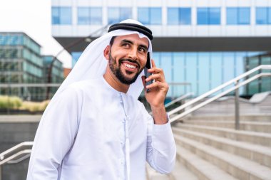 Arap Ortadoğu 'lu, Emirati Kandora giysili, şehirde geleneksel giysiler giyen Arap Müslüman iş adamı, şehir iş merkezinde geziniyor..