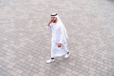 Arap Ortadoğu 'lu, Emirati Kandora giysili, şehirde geleneksel giysiler giyen Arap Müslüman iş adamı, şehir iş merkezinde geziniyor..