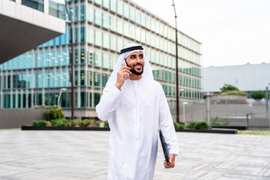 Arap Ortadoğu 'lu, Emirati Kandora giysili, şehirde geleneksel giysiler giyen Arap Müslüman iş adamı, şehir iş merkezinde geziniyor..