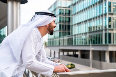 Arap Ortadoğu 'lu, Emirati Kandora giysili, şehirde geleneksel giysiler giyen Arap Müslüman iş adamı, şehir iş merkezinde geziniyor..