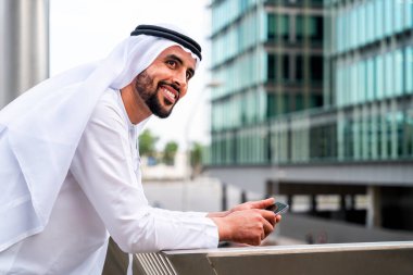 Arap Ortadoğu 'lu, Emirati Kandora giysili, şehirde geleneksel giysiler giyen Arap Müslüman iş adamı, şehir iş merkezinde geziniyor..