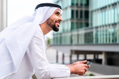 Arap Ortadoğu 'lu, Emirati Kandora giysili, şehirde geleneksel giysiler giyen Arap Müslüman iş adamı, şehir iş merkezinde geziniyor..