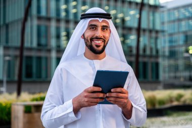 Arap Ortadoğu 'lu, Emirati Kandora giysili, şehirde geleneksel giysiler giyen Arap Müslüman iş adamı, şehir iş merkezinde geziniyor..