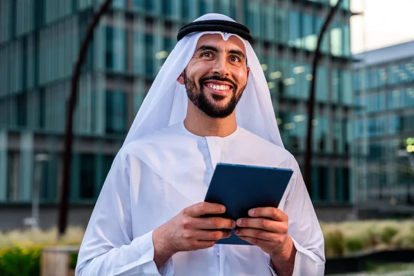 Arap Ortadoğu 'lu, Emirati Kandora giysili, şehirde geleneksel giysiler giyen Arap Müslüman iş adamı, şehir iş merkezinde geziniyor..