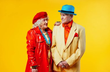 Stüdyoda renkli arka planda rol yapan şık parti kıyafetleri giyen yaşlı ve güzel bir çift. Üçüncü yaş ve kıdem hakkında kavramsal imaj, yaşlı insanlar kendilerini genç hissediyorlar..