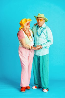 Stüdyoda renkli arka planda rol yapan şık parti kıyafetleri giyen yaşlı ve güzel bir çift. Üçüncü yaş ve kıdem hakkında kavramsal imaj, yaşlı insanlar kendilerini genç hissediyorlar..