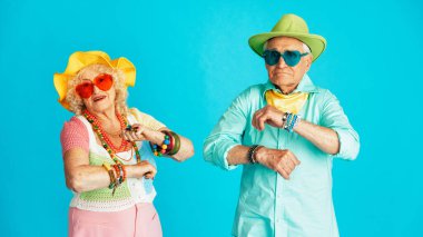 Stüdyoda renkli arka planda rol yapan şık parti kıyafetleri giyen yaşlı ve güzel bir çift. Üçüncü yaş ve kıdem hakkında kavramsal imaj, yaşlı insanlar kendilerini genç hissediyorlar..