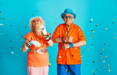 Stüdyoda renkli arka planda rol yapan şık parti kıyafetleri giyen yaşlı ve güzel bir çift. Üçüncü yaş ve kıdem hakkında kavramsal imaj, yaşlı insanlar kendilerini genç hissediyorlar..
