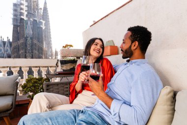 Sagrada Familia, Barcelona 'nın çatı katında buluşan çok ırklı, mutlu aşıklar şehir manzaralı bir terasta romantik aperatifler, turizm ve insan yaşam tarzı hakkında kavramlar