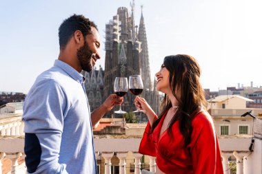 Sagrada Familia, Barcelona 'nın çatı katında buluşan çok ırklı, mutlu aşıklar şehir manzaralı bir terasta romantik aperatifler, turizm ve insan yaşam tarzı hakkında kavramlar