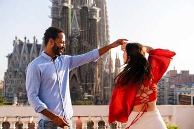 Sagrada Familia, Barcelona 'nın çatı katında buluşan çok ırklı, mutlu aşıklar şehir manzaralı bir terasta romantik aperatifler, turizm ve insan yaşam tarzı hakkında kavramlar