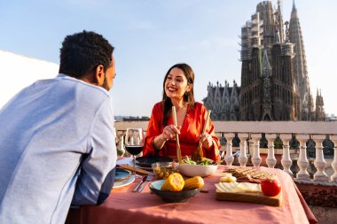 Sagrada Familia, Barcelona 'nın çatı katında buluşan çok ırklı, mutlu aşıklar şehir manzaralı bir terasta romantik aperatifler, turizm ve insan yaşam tarzı hakkında kavramlar