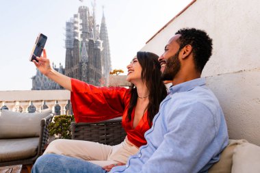 Sagrada Familia, Barcelona 'nın çatı katında buluşan çok ırklı, mutlu aşıklar şehir manzaralı bir terasta romantik bir buluşma, turizm ve insan yaşam tarzı hakkında kavramlar