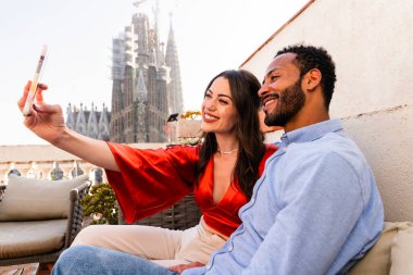 Sagrada Familia, Barcelona 'nın çatı katında buluşan çok ırklı, mutlu aşıklar şehir manzaralı bir terasta romantik bir buluşma, turizm ve insan yaşam tarzı hakkında kavramlar