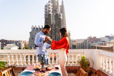 Sagrada Familia, Barcelona 'nın çatı katında buluşan çok ırklı, mutlu aşıklar şehir manzaralı bir terasta romantik aperatifler, turizm ve insan yaşam tarzı hakkında kavramlar