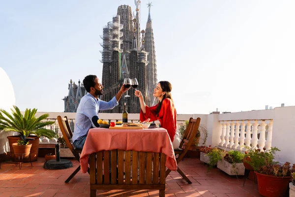 Sagrada Familia, Barcelona 'nın çatı katında buluşan çok ırklı, mutlu aşıklar şehir manzaralı bir terasta romantik aperatifler, turizm ve insan yaşam tarzı hakkında kavramlar