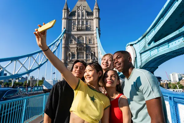 Londra 'da, Tower Bridge bölgesinde buluşup eğlenen çok ırklı genç arkadaş grubu gençlik yaşam tarzı, seyahat ve turizm konseptleri