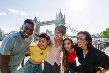 Londra 'da, Tower Bridge bölgesinde buluşup eğlenen çok ırklı genç arkadaş grubu gençlik yaşam tarzı, seyahat ve turizm konseptleri