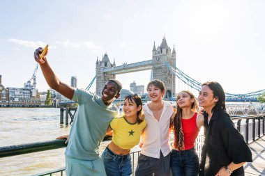 Londra 'da, Tower Bridge bölgesinde buluşup eğlenen çok ırklı genç arkadaş grubu gençlik yaşam tarzı, seyahat ve turizm konseptleri