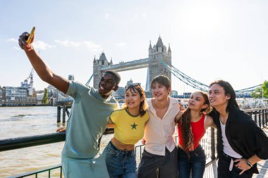 Londra 'da, Tower Bridge bölgesinde buluşup eğlenen çok ırklı genç arkadaş grubu gençlik yaşam tarzı, seyahat ve turizm konseptleri