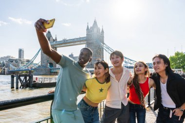 Londra 'da, Tower Bridge bölgesinde buluşup eğlenen çok ırklı genç arkadaş grubu gençlik yaşam tarzı, seyahat ve turizm konseptleri