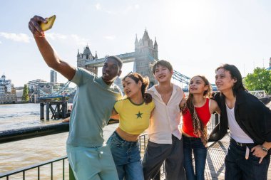 Londra 'da, Tower Bridge bölgesinde buluşup eğlenen çok ırklı genç arkadaş grubu gençlik yaşam tarzı, seyahat ve turizm konseptleri