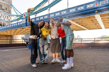 Londra 'da, Tower Bridge bölgesinde buluşup eğlenen çok ırklı genç arkadaş grubu gençlik yaşam tarzı, seyahat ve turizm konseptleri