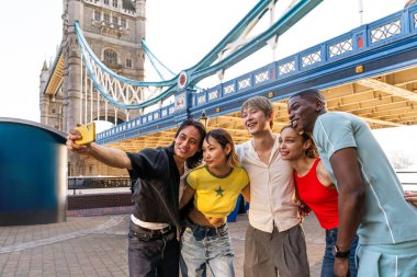Londra 'da, Tower Bridge bölgesinde buluşup eğlenen çok ırklı genç arkadaş grubu gençlik yaşam tarzı, seyahat ve turizm konseptleri
