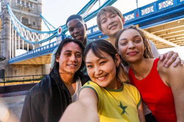 Londra 'da, Tower Bridge bölgesinde buluşup eğlenen çok ırklı genç arkadaş grubu gençlik yaşam tarzı, seyahat ve turizm konseptleri