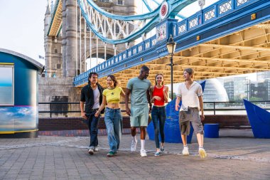 Londra 'da, Tower Bridge bölgesinde buluşup eğlenen çok ırklı genç arkadaş grubu gençlik yaşam tarzı, seyahat ve turizm konseptleri