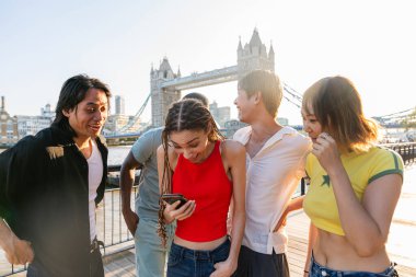 Londra 'da, Tower Bridge bölgesinde buluşup eğlenen çok ırklı genç arkadaş grubu gençlik yaşam tarzı, seyahat ve turizm konseptleri