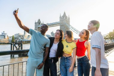Londra 'da, Tower Bridge bölgesinde buluşup eğlenen çok ırklı genç arkadaş grubu gençlik yaşam tarzı, seyahat ve turizm konseptleri
