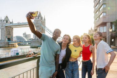Londra 'da, Tower Bridge bölgesinde buluşup eğlenen çok ırklı genç arkadaş grubu gençlik yaşam tarzı, seyahat ve turizm konseptleri