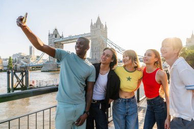 Londra 'da, Tower Bridge bölgesinde buluşup eğlenen çok ırklı genç arkadaş grubu gençlik yaşam tarzı, seyahat ve turizm konseptleri