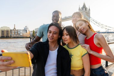 Londra 'da, Tower Bridge bölgesinde buluşup eğlenen çok ırklı genç arkadaş grubu gençlik yaşam tarzı, seyahat ve turizm konseptleri