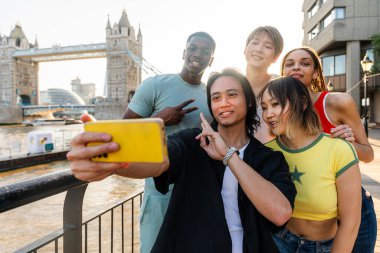 Londra 'da, Tower Bridge bölgesinde buluşup eğlenen çok ırklı genç arkadaş grubu gençlik yaşam tarzı, seyahat ve turizm konseptleri