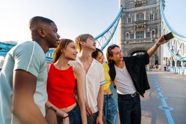 Londra 'da, Tower Bridge bölgesinde buluşup eğlenen çok ırklı genç arkadaş grubu gençlik yaşam tarzı, seyahat ve turizm konseptleri
