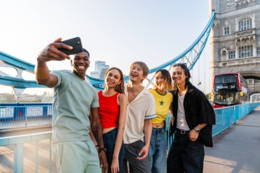 Londra 'da, Tower Bridge bölgesinde buluşup eğlenen çok ırklı genç arkadaş grubu gençlik yaşam tarzı, seyahat ve turizm konseptleri