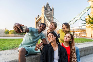 Londra 'da, Tower Bridge bölgesinde buluşup eğlenen çok ırklı genç arkadaş grubu gençlik yaşam tarzı, seyahat ve turizm konseptleri