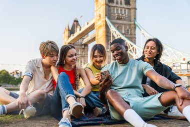 Londra 'da, Tower Bridge bölgesinde buluşup eğlenen çok ırklı genç arkadaş grubu gençlik yaşam tarzı, seyahat ve turizm konseptleri