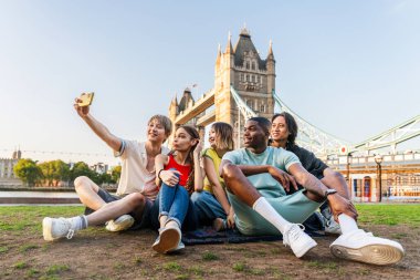 Londra 'da, Tower Bridge bölgesinde buluşup eğlenen çok ırklı genç arkadaş grubu gençlik yaşam tarzı, seyahat ve turizm konseptleri