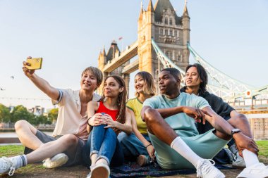 Londra 'da, Tower Bridge bölgesinde buluşup eğlenen çok ırklı genç arkadaş grubu gençlik yaşam tarzı, seyahat ve turizm konseptleri