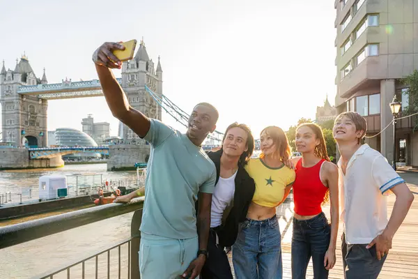 Londra 'da, Tower Bridge bölgesinde buluşup eğlenen çok ırklı genç arkadaş grubu gençlik yaşam tarzı, seyahat ve turizm konseptleri
