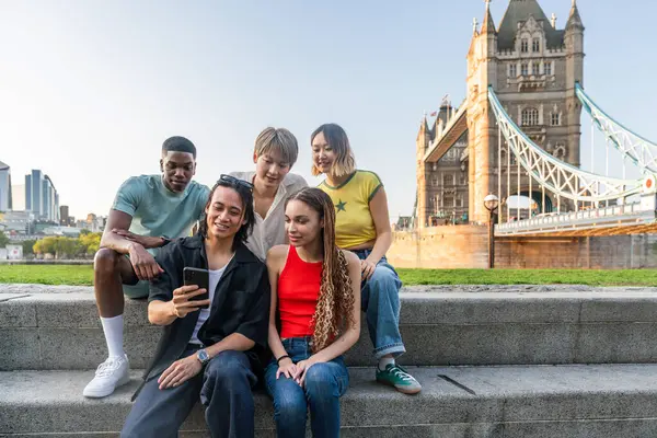 Londra 'da, Tower Bridge bölgesinde buluşup eğlenen çok ırklı genç arkadaş grubu gençlik yaşam tarzı, seyahat ve turizm konseptleri