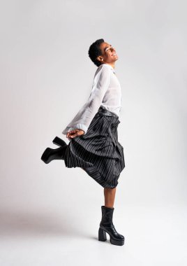 Akışkan cinsiyet Latin Latin asıllı adam stüdyoda şık kıyafetler, LGBTQ konseptleri, cinsiyetsiz ve çeşitlilikle poz veriyor.