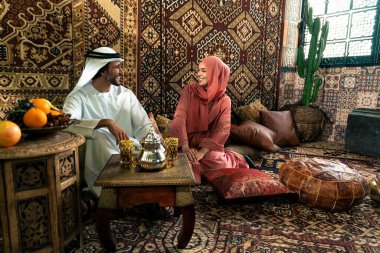 Emirati 'li genç bir çift geleneksel Arap kafesinde vakit geçiriyor. Kandura giyen kadın ve erkek Dubai 'den abaya sohbet ediyorlar..